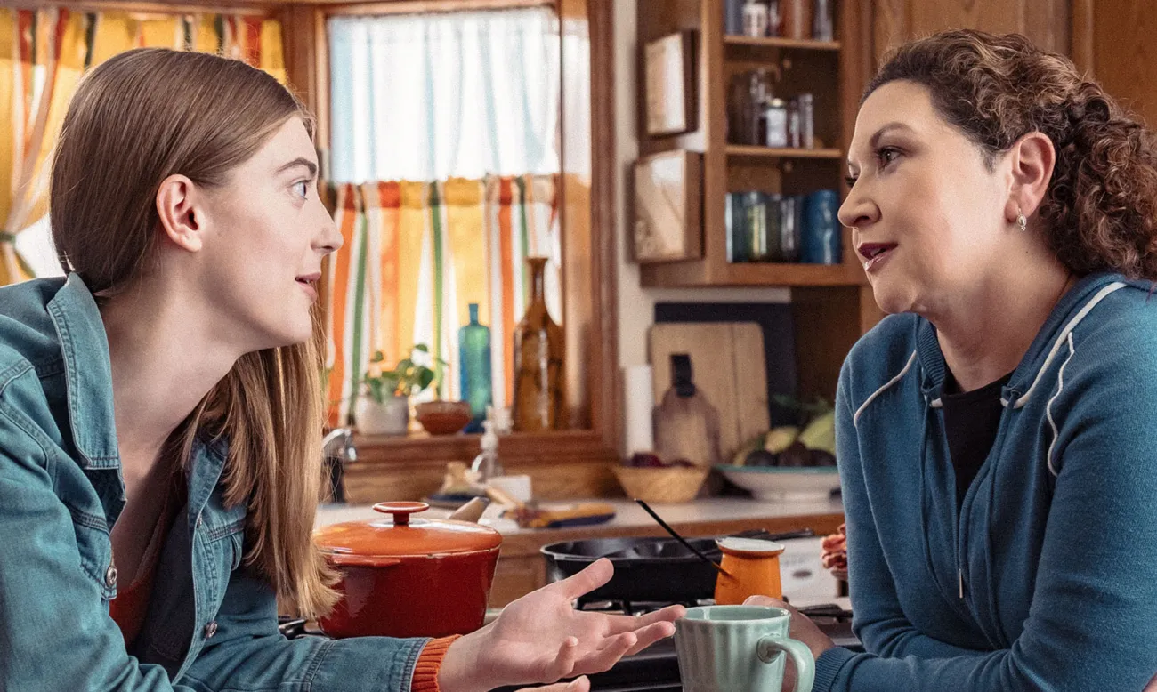 Guardian speaking to teen in a kitchen.